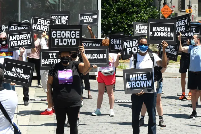 A photo of protesters holding signs featuring the names of police brutality victims